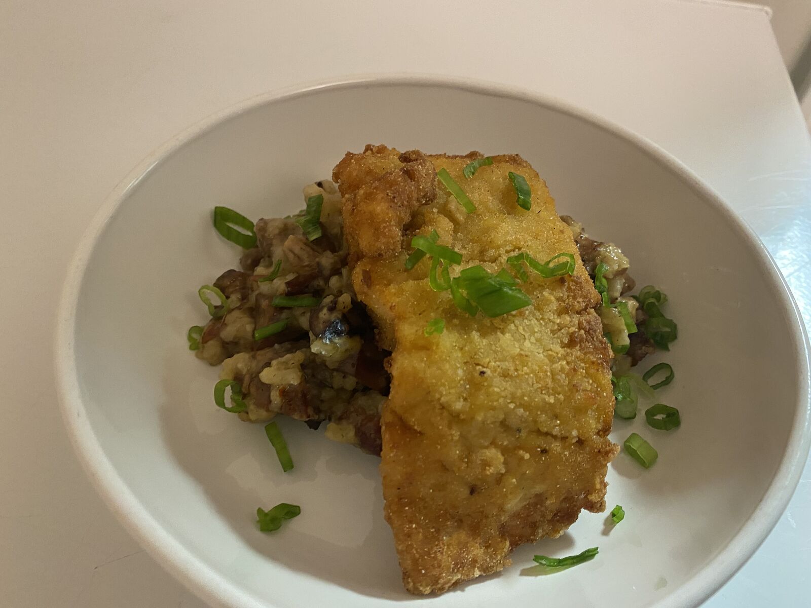 Pan-fried fish over a grain salad, plated on a white dish