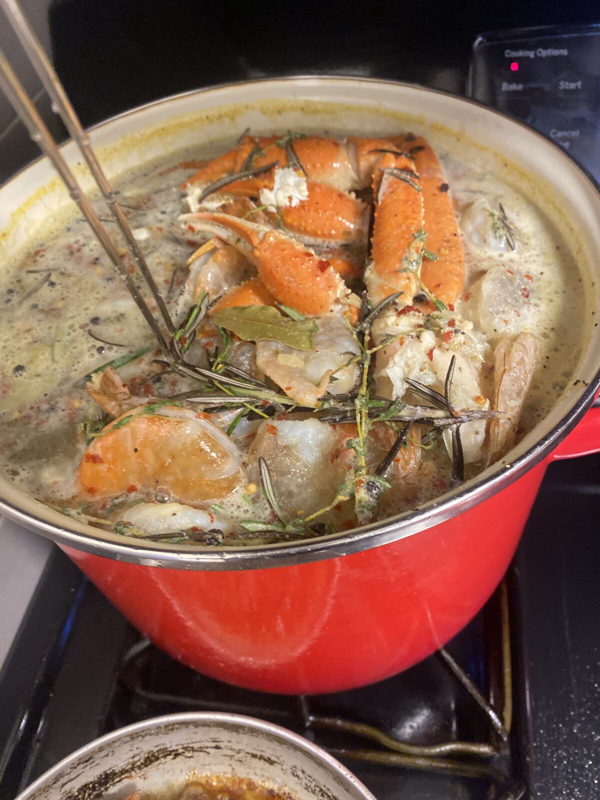 Seafood boil with snow crab simmering in a red pot